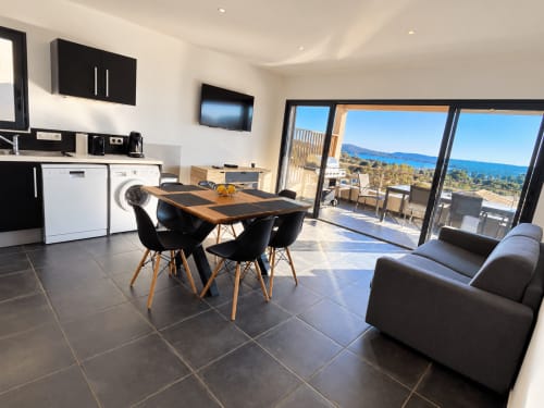 Appartement moderne ouvert aux Les Villas d'A Storia à Zonza avec vue mer, salle à manger, cuisine et paysage côtier