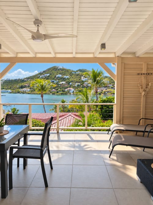 Beachfront bungalow terrace at Les Balcons D'Oyster Pond, Saint-Martin with sea views, palm trees, and lounge seating