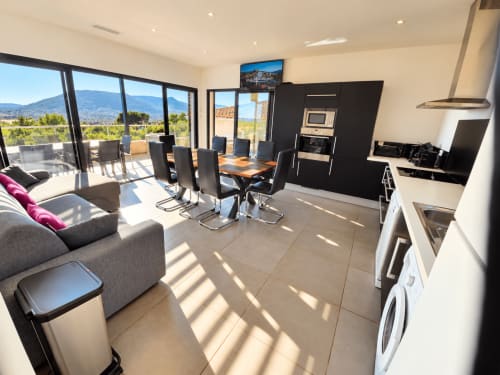 Appartement moderne décloisonné aux Villas d'A Storia en Corse avec table à manger, cuisine, vue sur mer depuis le balcon, et