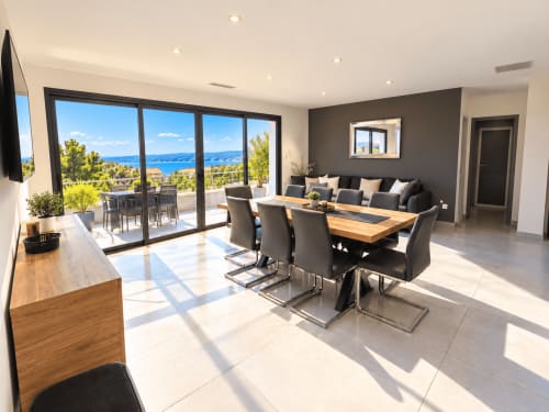 Salle à manger contemporaine avec vue sur mer aux Villas d'A Storia à Zonza, table en bois, chaises noires et panorama océanique