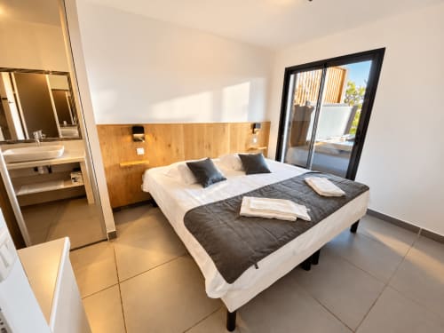 Chambre moderne aux Villas d'A Storia à Zonza avec vue mer, tête de lit en bois et salle de bain attenante