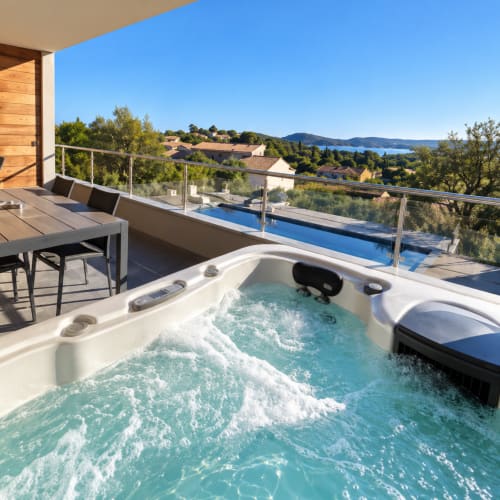 Jacuzzi luxueux sur terrasse avec vue sur la baie de Zonza, piscine privée et espace repas face à la mer