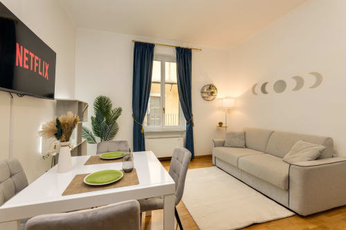 Moderna sala living con zona pranzo, divano beige, TV e vista sulla città a Buonanotte Colosseo a Roma