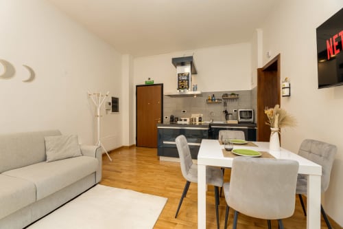 Moderno appartamento open space a Roma con tavolo da pranzo, divano, angolo cottura e TV—Colosseum Sweet Life