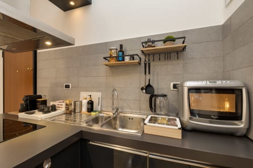 Cucina moderna in appartamento romano con lavello in acciaio inossidabile, microonde, mensole in legno e rivestimento in piastrelle grigie