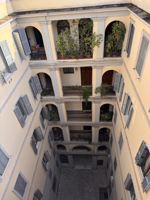 Vista del cortile del Buonanotte Colosseo B&B a Roma, edificio pluripiano con finestre ad arco, persiane, piante in vaso