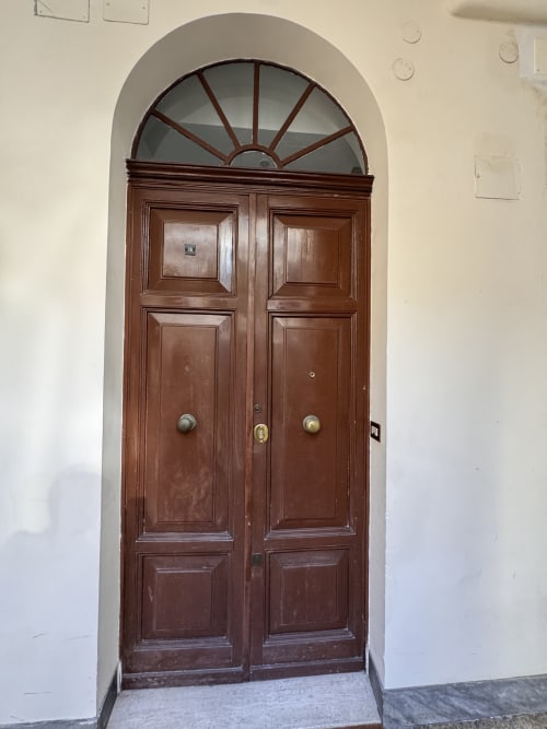Doppia porta in legno con finestra a ventaglio all'ingresso dell'hotel Buonanotte Colosseo a Roma