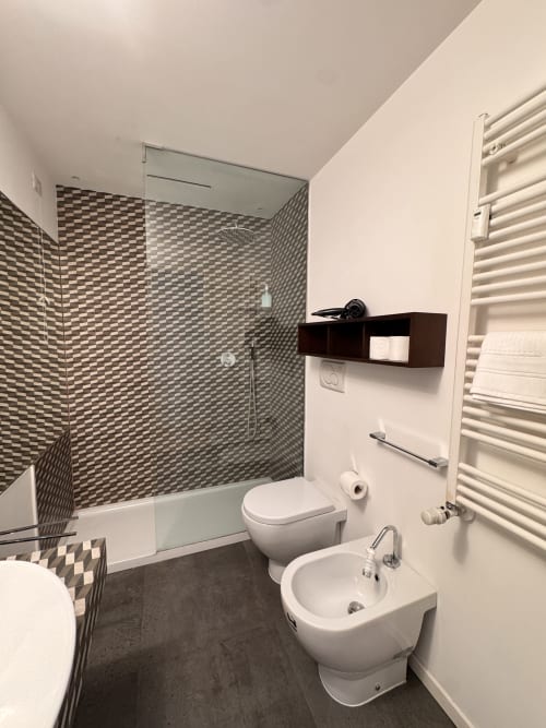 Bagno moderno al Buonanotte Colosseo Roma con doccia a scacchi, toilette, bidet e scaldasalviette bianco