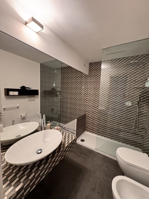 Bagno moderno a Buonanotte Colosseo a Roma con doppi lavabi, doccia con piastrelle geometriche, wc e bidet