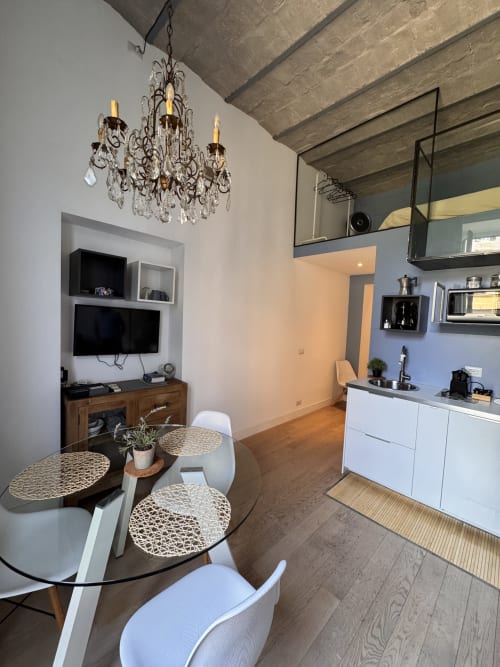 Monolocale moderno a Buonanotte Colosseo Roma con zona pranzo, angolo cottura, TV, lampadario e soffitto con travi in legno