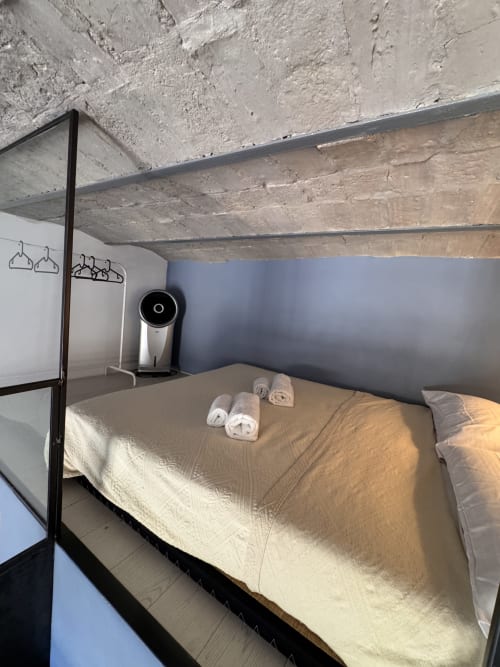 Camera moderna al Buonanotte Colosseo a Roma con letto a baldacchino, asciugamani arrotolati, soffitto in cemento e viste sulla città