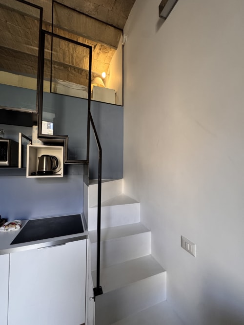 Moderna cucina in RESIDENZA LABICANA presso Buonanotte Colosseo Roma BnB con armadi bianchi, piano cottura nero, scale e
