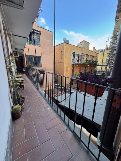 Terrazza stretta con balaustra nera e piante in vaso con vista su edifici colorati nel centro storico di Roma, Buonanotte