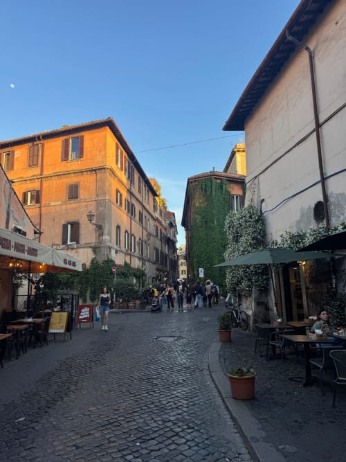 Affascinante via lastricata a Roma con edifici storici colorati e caffè all'aperto vicino a Buonanotte Colosseo