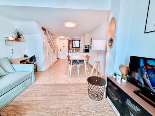 Modern Tenerife apartment living room with sofa, TV, dining area, and kitchen in Playa de las Américas