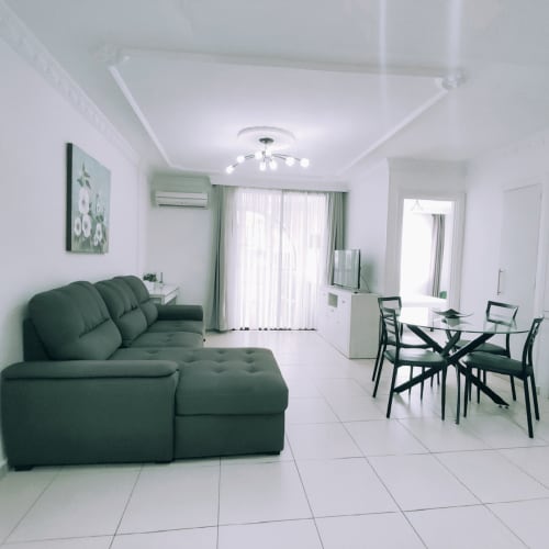 Modern apartment living room at Manage Home Tenerife in Playa de las Américas with green sofa, dining area, and city views