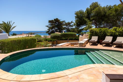 Piscina curva con aguas turquesas con vistas al mar Mediterráneo en Villas Etnia, Sant Lluís