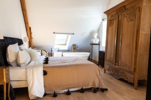 Chambre élégante du Domaine du Tertre Ychot à Dol de Bretagne avec mobilier en bois, literie crème et vue sur le jardin