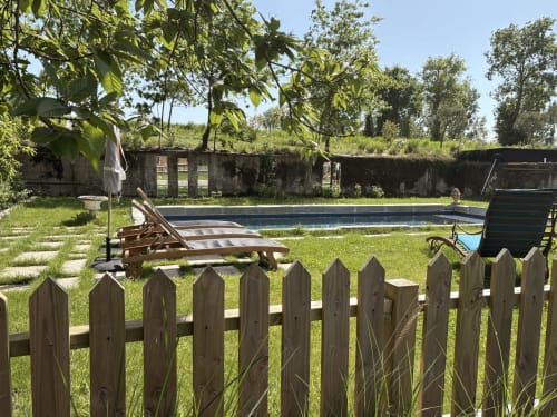 Clôture en bois surplombant une piscine paisible et jardin avec transats au Domaine du Tertre Ychot, Dol de Bretagne