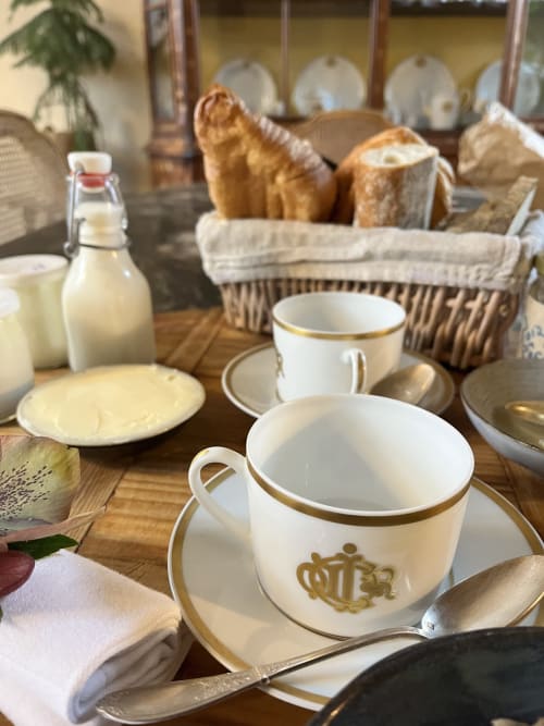 Table de petit-déjeuner élégante au Domaine du Tertre Ychot avec pain frais, bouteille de lait et service de table aux finitions dorées à Dol