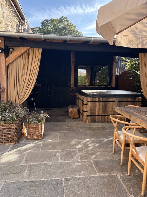 Terrasse extérieure avec baignoire chaude en bois, chaises longues et parasols au Domaine du Tertre Ychot, Dol de Bretagne
