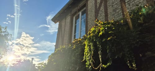 Façade en pierre de la Villa Aliénor aux murs couverts de lierre, grandes fenêtres et ciel bleu aux Andelys