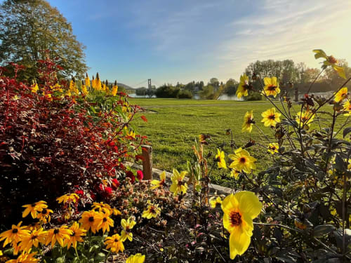Jardin coloré aux fleurs jaunes et rouges avec vue sur les champs verdoyants et le pont de la Villa Aliénor, Les Andelys