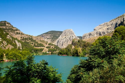 Lago turquesa rodeado de acantilados calcáreos y vegetación verde cerca del hotel The Alma Suite en Álora, España