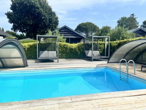 Piscine aux eaux cristallines avec terrasse en bois et abris de détente aux Gîtes D'armor, Tréguidel, France