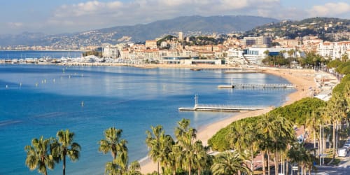 Plage de Cagnes-sur-Mer avec palmiers, rivage sablonneux et collines méditerranéennes