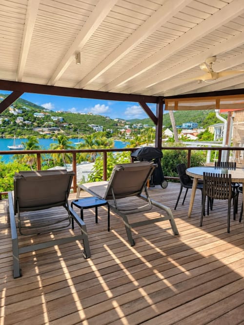 Sunny terrace at Les Balcons D'oyster Pond with lounge chairs, dining table, and panoramic sea view of Saint-Martin bay with