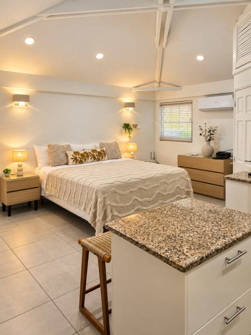 Modern bedroom at Les Balcons D'Oyster Pond bungalow with sea view, wood furniture, warm lighting, and tiled flooring.
