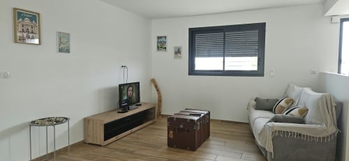 Séjour moderne de la Villa Azura à Carcassonne avec salon confortable, télévision, mobilier bois et lumière naturelle abondante