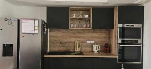 Cuisine moderne avec placards noirs, crédence en bois, électroménagers acier inoxydable et vitrine à Villa Azura, Carcassonne