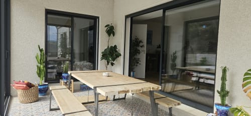 Terrasse moderne avec table en bois, bancs, plantes en pot et portes vitrées à Villa Azura à Carcassonne