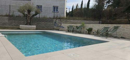Piscine privée de la Villa Azura à Carcassonne avec chaises longues, terrasse en pierre et jardin luxuriant