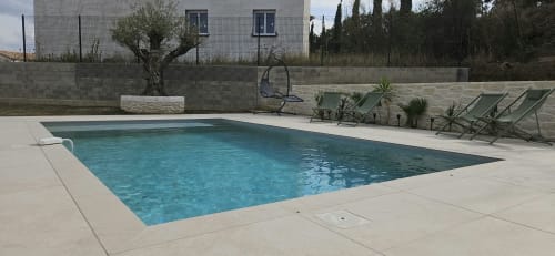 Piscine privée rectangulaire à la Villa Azura à Carcassonne avec transats, murs en pierre et jardin méditerranéen