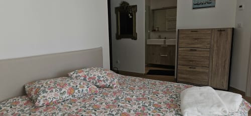 Chambre à Villa Azura, Carcassonne avec literie fleurie, salle de bains attenante et mobilier en bois