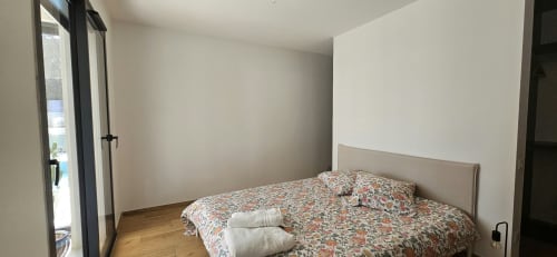 Chambre avec literie à motifs floraux et tête de lit beige à la Villa Azura, villa à Carcassonne avec vue sur la piscine