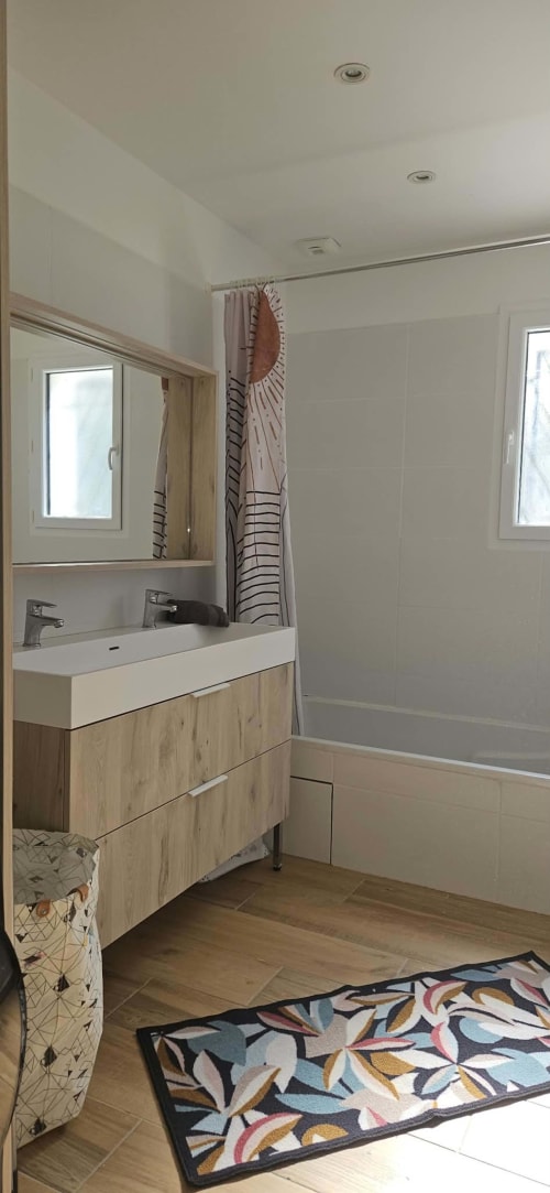 Salle de bain moderne de la Villa Azura à Carcassonne avec vasque en bois, miroir, douche et tapis de bain coloré