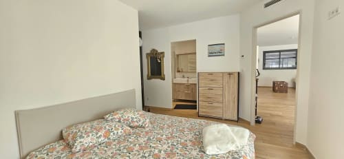 Chambre moderne à la Villa Azura, Carcassonne, avec literie florale, rangements en bois et accès à la salle de bain attenante
