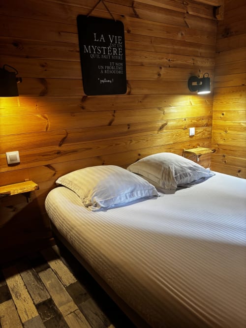 Chambre chaleureuse au gîte d'Armor avec lit blanc, coussins et décoration murale inspirante à Tréguídel