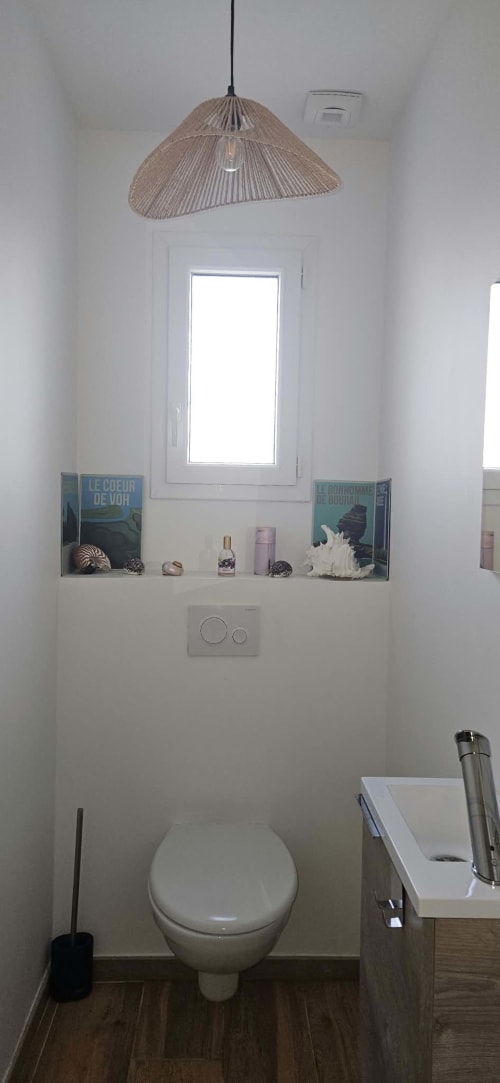 Salle de bain contemporaine de la Villa Azura à Carcassonne, avec toilettes blanches, suspension en osier et étagère décorée