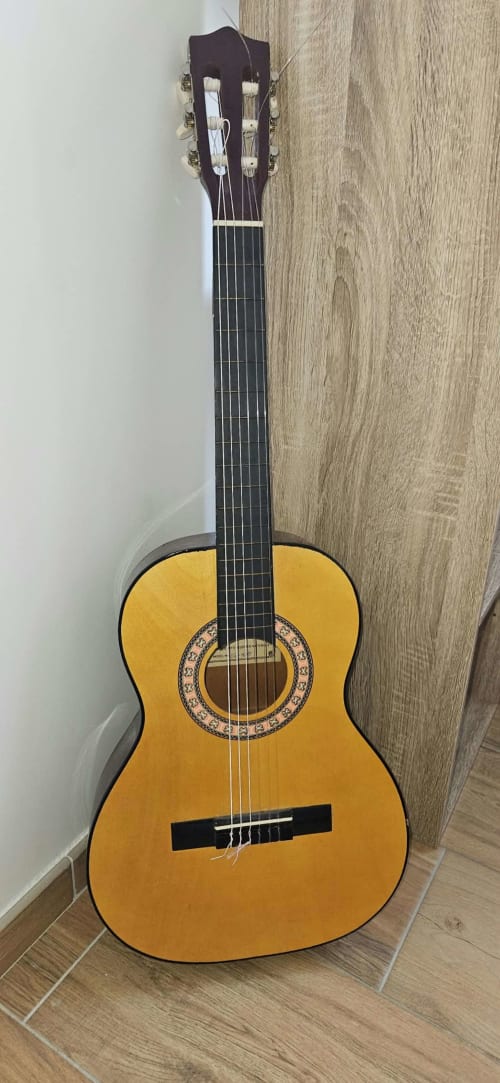 Guitare acoustique classique à vernis jaune appuyée contre le mur de la Villa Azura à Mi Casa Es Su Casa, Carcassonne