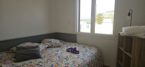 Chambre lumineuse aux draps floraux colorés, grandes fenêtres donnant sur la piscine, équipements modernes à Villa Azura