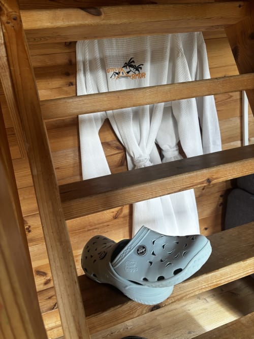 Étagères en bois avec serviettes blanches pliées et chaussons aux Gites D'armor, Treguidel