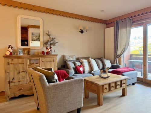 Séjour douillet de l'appartement HAUTS BOIS à La Plagne Ski Confort avec mobilier en bois, canapé gris, cheminée et montagne