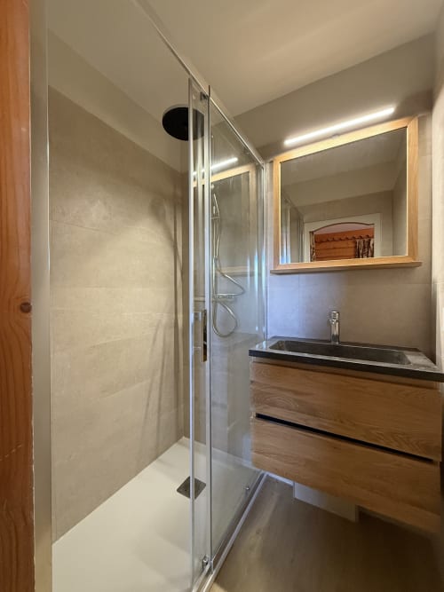 Salle de bain moderne avec douche à l'italienne, vanité en bois et plan noir, miroir à La Plagne Ski Confort
