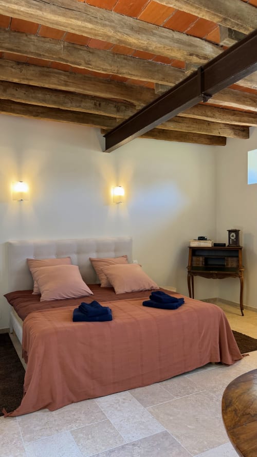 Chambre confortable à la Cloffy B&B à Nouans-les-Fontaines avec poutres apparentes, literie terracotta et éclairage ambiant
