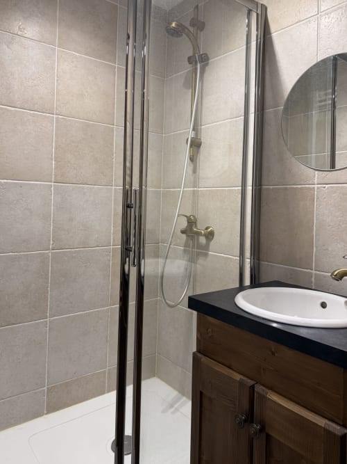 Salle de bain moderne avec douche à l'italienne, carrelage beige, meuble-vasque en bois et lavabo blanc à La Plagne Ski Confort